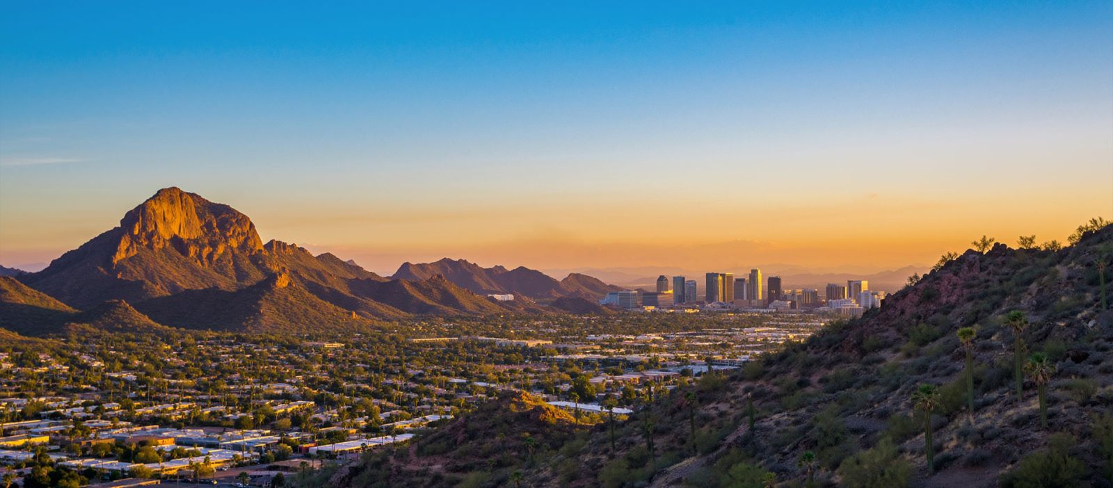 Panoramic view of the Scottsdale, Arizona skyline at sunset, featuring modern downtown architecture and desert landscapes under a colorful desert sky.